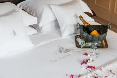 a bottle of champagne and flowers on a bed at La Maison Ottomane in Chania Town
