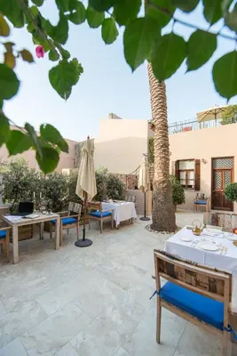 a patio with tables and umbrellas and a palm tree at La Maison Ottomane in Chania Town
