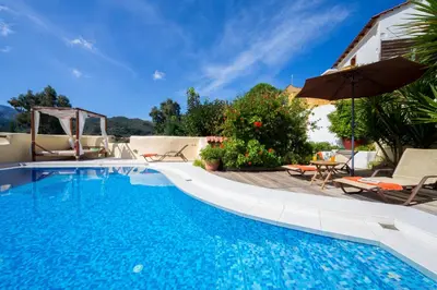 a swimming pool with an umbrella and chairs and a table at Verekinthos Villas - Pool, Hot Tub, BBQ, Kids Playground, Stunning Mountain Views in Gerolakkos