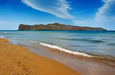 a beach with a small island in the water at Thodorou Village in Agia Marina Nea Kydonias