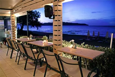 a row of tables and chairs with a view of the ocean at Esperides Beach Hotel Apartments in Stalos