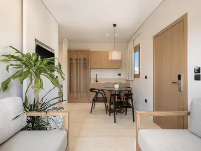 a living room and kitchen with a table and chairs at Esperides Beach Hotel Apartments in Stalos
