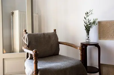 a chair in a room with a vase on a table at Basilikos traditional house, 10' from Falasarna in Kissamos