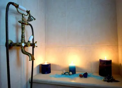 a bathroom with a shower and two candles on a shelf at Basilikos traditional house, 10' from Falasarna in Kissamos