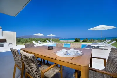 a wooden table and chairs with a view of the ocean at Beach Villas in Chania Town