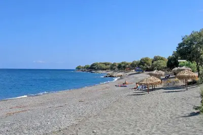 a beach with straw umbrellas and people on the beach at Beach Villas in Chania Town