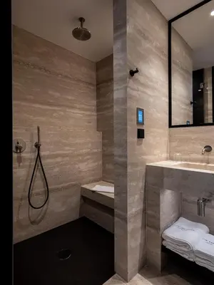 a bathroom with a shower and a sink and a mirror at The Tanneries Hotel & Spa - a Member of Design Hotels in Chania Town