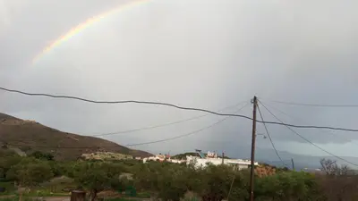 a rainbow in the sky over a hill with a house at TRADITIONAL HOUSE MARIA in Azoyirás