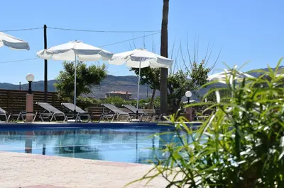 a swimming pool with chairs and umbrellas at Odos Oneiron Tavronitis Bay in Tavronitis
