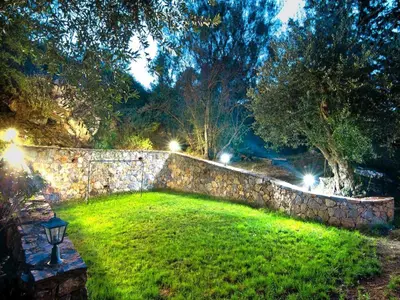 a stone wall with lights in a yard at night at Holiday home with pool in Kalamítsion Alexándrou