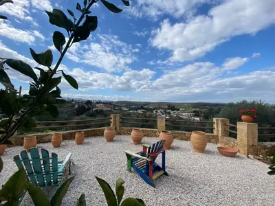 a patio with chairs and vases on a hill at ARIALKiS - ΑΡΙΑΛΚίΣ in Plataniás