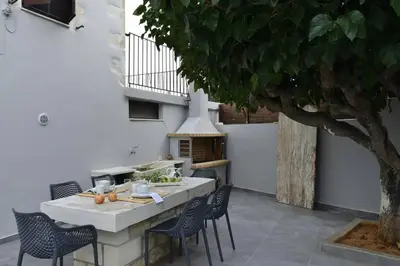 a outdoor kitchen with a table and chairs and a tree at Villa Christini a luxury villa with amazing views in Tzitzifés