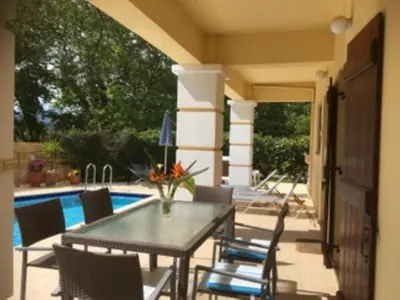 a patio with a table and chairs next to a pool at Villa Spilia Homeleader in Spiliá