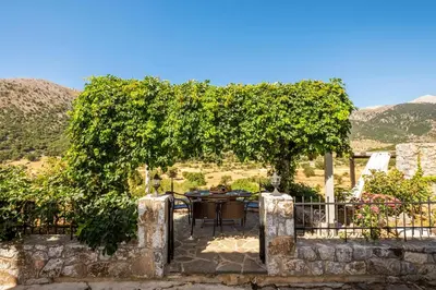 a patio with a table and chairs under a tree at Private Stone villa-Pool and Maountain view in Karés