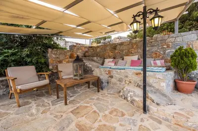 a patio with a stone wall and a table and chairs at Private Stone villa-Pool and Maountain view in Karés