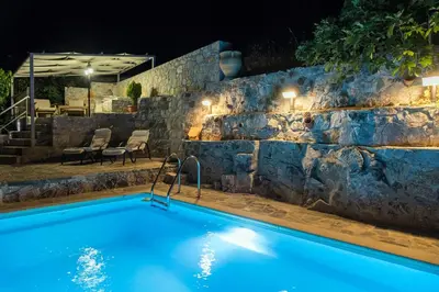 a swimming pool at night with a stone wall at Private Stone villa-Pool and Maountain view in Karés