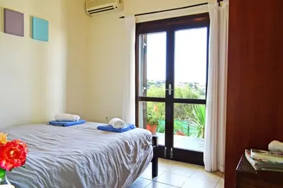 a bedroom with a bed and a sliding glass door at Villa Ravdoucha Homeleader in Ravdhoúkha