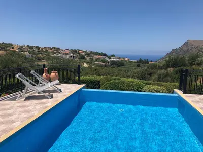 a blue swimming pool with a view of the ocean at Villa Ravdoucha Homeleader in Ravdhoúkha