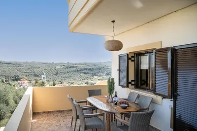 a patio with a wooden table and chairs on a balcony at Villa Hibiscus in Spiliá