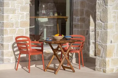 a wooden table with two chairs and a bowl of fruit at Canna Villa in Vamos