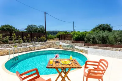 a table and chairs next to a swimming pool at Canna Villa in Vamos