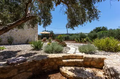 a garden with a stone wall and plants at Canna Villa in Vamos
