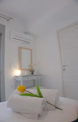 a white bedroom with a bed with a yellow flower on it at New Big Modern City Center Apartment in Chania Town