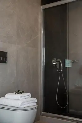 a bathroom with a shower and a toilet and towels at Morum City Hotel Chania in Chania Town
