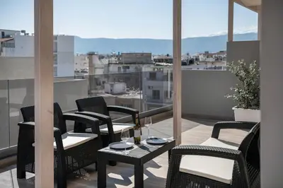 a balcony with chairs and a table with wine glasses at Morum City Hotel Chania in Chania Town