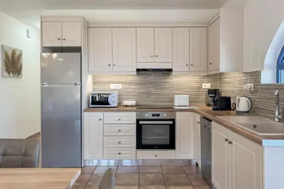 a kitchen with white cabinets and a stainless steel refrigerator at Pano Stalos Villas in Stalos