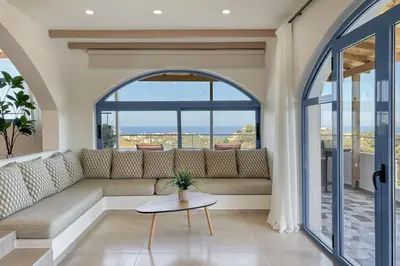 a living room with a couch and a large window at Pano Stalos Villas in Stalos