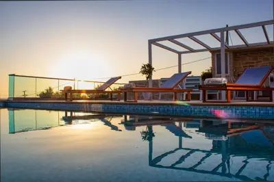 a swimming pool with two lounge chairs and the sunset at Luxuryvillaschania Kore-Falasarna beach in Falasarna