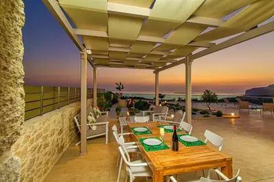 a patio with a table and chairs and the sunset at 2 steps Falasarna beach-Liakos- Homeleader in Falasarna