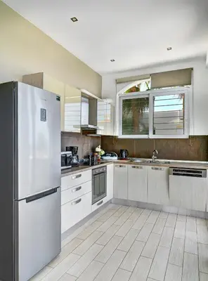 a kitchen with white cabinets and a refrigerator at Villa Anemos by Estia in Kalathas
