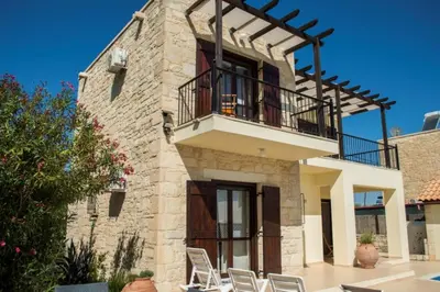 a stone house with a balcony and chairs at Villa Darmarohori Homeleader in Darmarochori