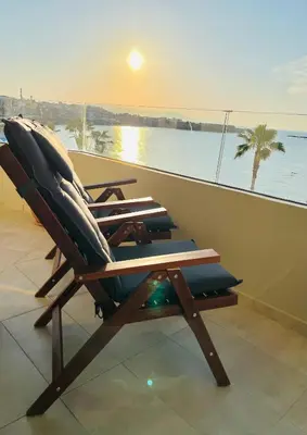 a deck chair sitting on a balcony with a view of the ocean at zonapartments A sea view-city center in Chania Town