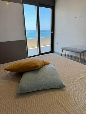 a pillow on a bed with a view of the beach at zonapartments A sea view-city center in Chania Town