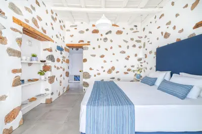 a bedroom with a white bed and a wall with rocks at FantaSea Luxury Suite in Khóra Sfakíon