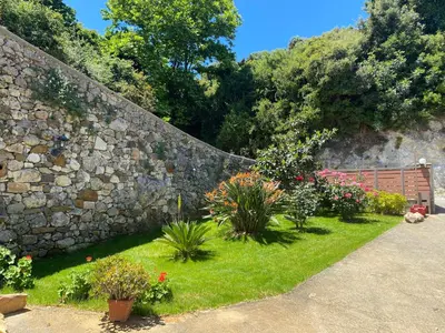 a garden with flowers in front of a stone wall at Serenity Resort in Vrísai