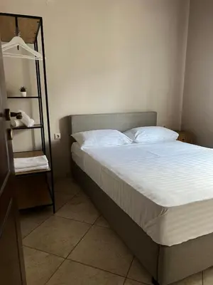 a bedroom with a bed with white sheets and a shelf at Serenity Resort in Vrísai