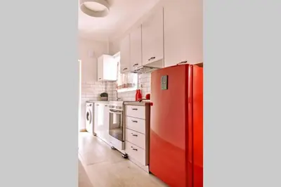 a red refrigerator in a kitchen with white cabinets at Natasha's Luxury apartment by the sea in Galatás