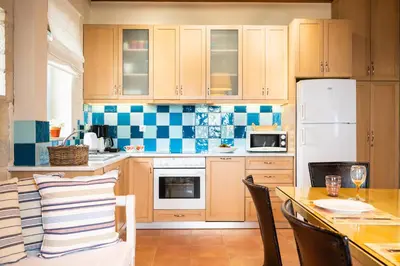 a kitchen with wooden cabinets and a table with chairs at Beachfront villa Turquoise with private pool, BBQ and ping pong table in Chania Town