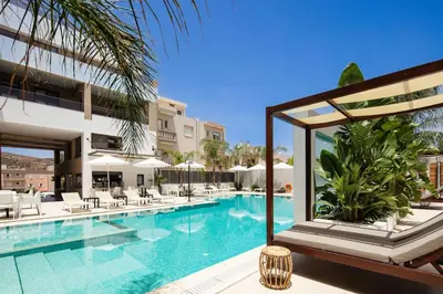 a swimming pool with chairs and a building at Sapphire Blue Suites in Kissamos