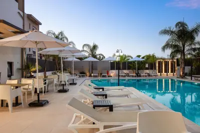 a pool with white chairs and tables and umbrellas at Sapphire Horizon Suites in Kissamos