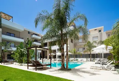 an exterior view of a resort with a pool and palm trees at Sapphire Horizon Suites in Kissamos