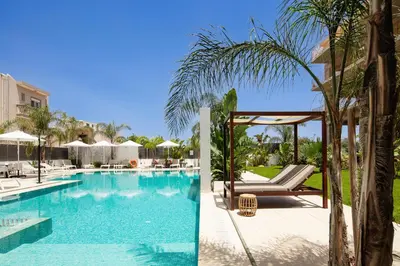 a pool at a resort with chairs and a palm tree at Sapphire Horizon Suites in Kissamos