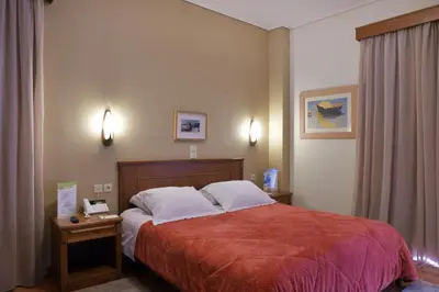 a bedroom with a bed with a red blanket and white pillows at Sissy Village All Suite Hotel in Kounoupidhianá