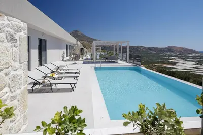 a pool on the side of a building with chairs at Falasarna village in Falasarna