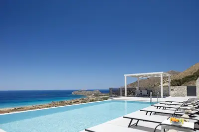 a pool with chairs and the ocean in the background at Falasarna village in Falasarna