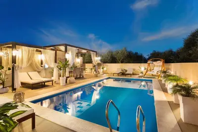 a swimming pool in a backyard at night at Villa Elisabeth View in Plataniás